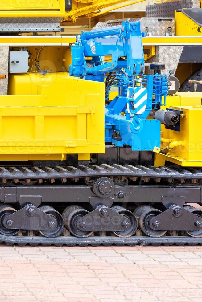 A blue hydraulic crane on a yellow crawler mobile construction platform. photo