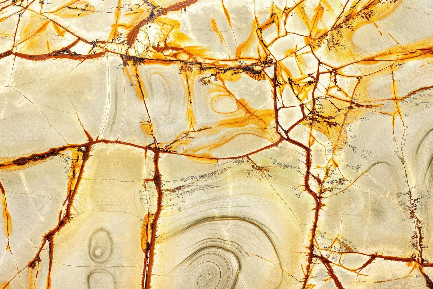 Cracked texture on the surface of yellow-green marble with brown lines and stains. photo