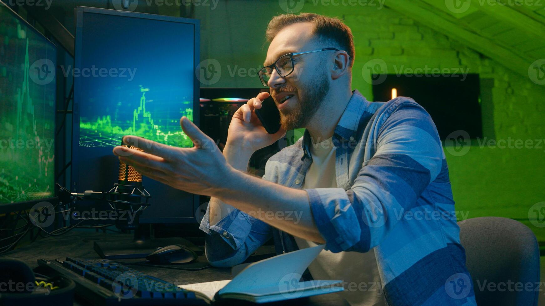 Smiling happy Caucasian broker man guy developer crypto businessman discussing mobile phone at home neon trader male work computer nighttime freelancer business good result thumb up sign stock trade photo