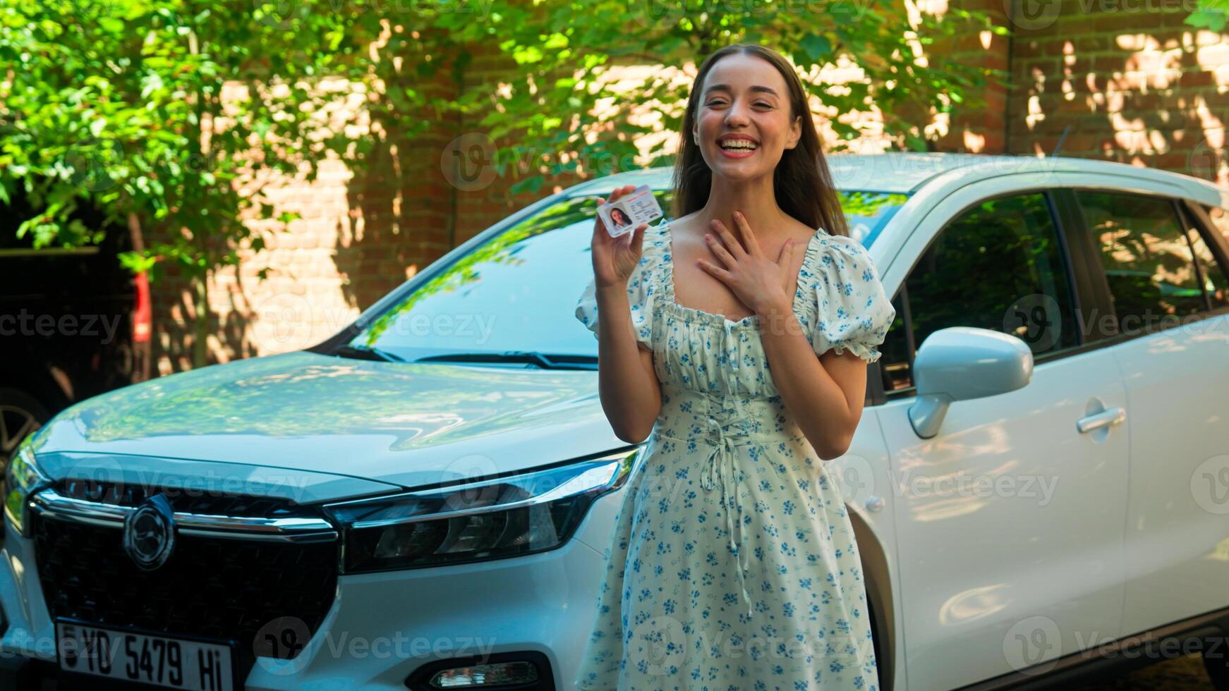 Happy excited amazed Caucasian woman female girl student client buyer buy new car automobile showing driver license successfully passed exam test driving lessons celebrating excitement at city street photo