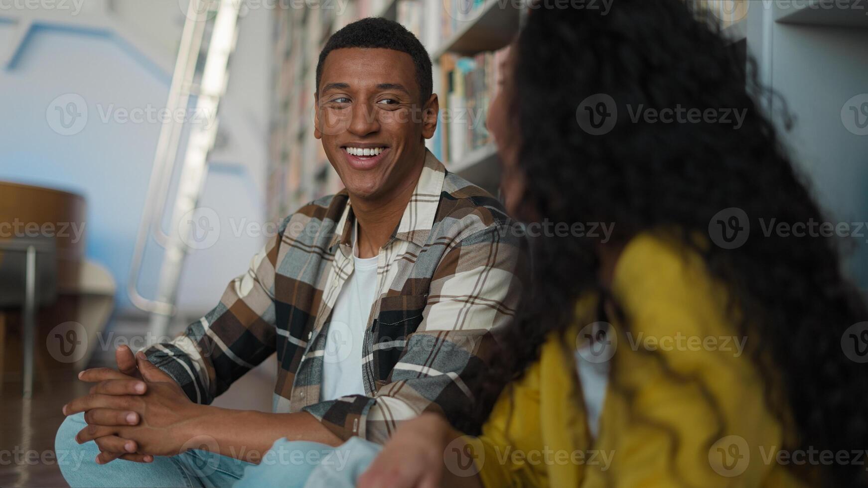 African American man Caucasian Hispanic woman students learning sitting together floor talking conversation dialogue reading club discussion library classmates university high school college studying photo