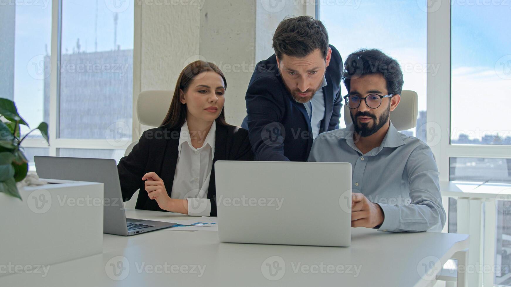 Diverse team corporate coworkers working laptops in office male business coach mentor boss businessman helping employees with computer work training new workers help interns check explain data project photo