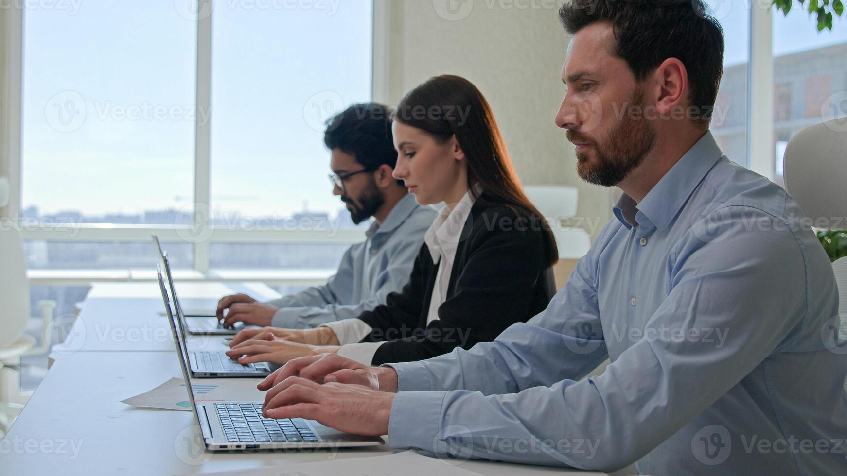 Moving shot row of multiethnic business people typing laptop pressing buttons on computer in modern office focused team managers staff businesswoman and businessmen working remote in coworking company photo