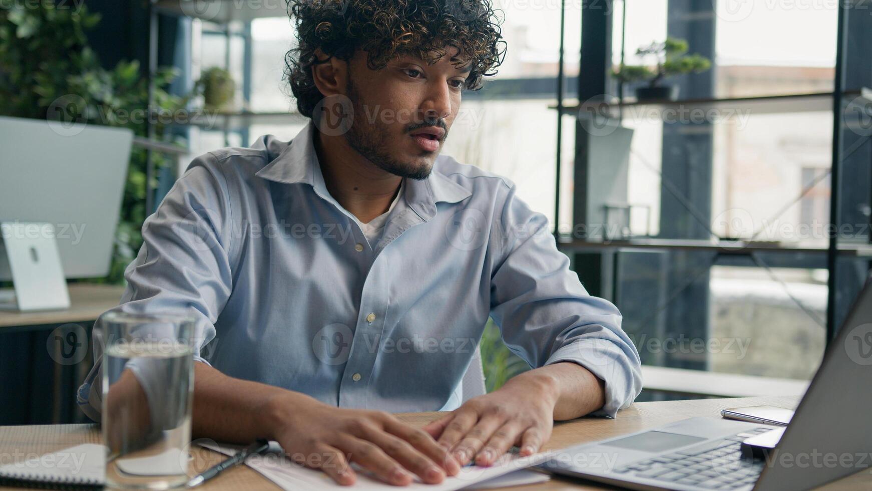 Frustrated Indian business man Arabian businessman at office desk difficult work solve issue problem with paperwork documents loss finances budget trouble feel stress disappointed negative emotions photo