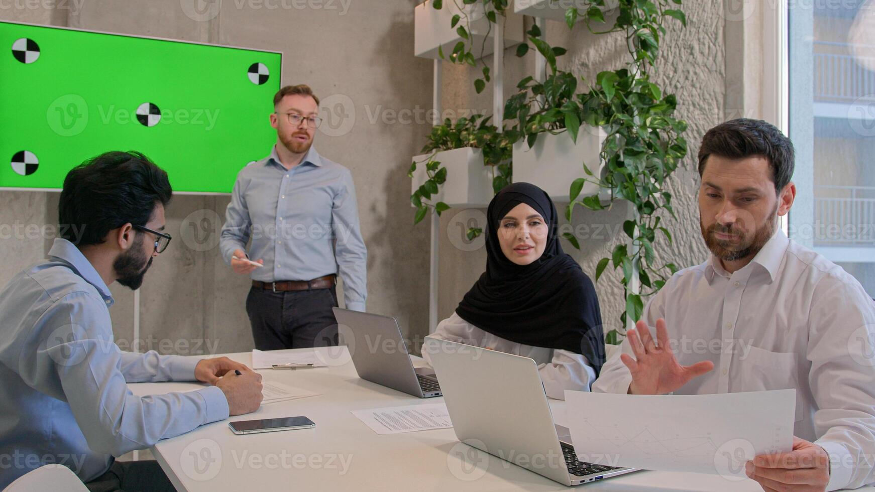 Team employees corporate staff businessmen multiracial businesswoman discuss documents at office conference ceo manager leading business meeting show presentation on green screen chroma key copy space photo