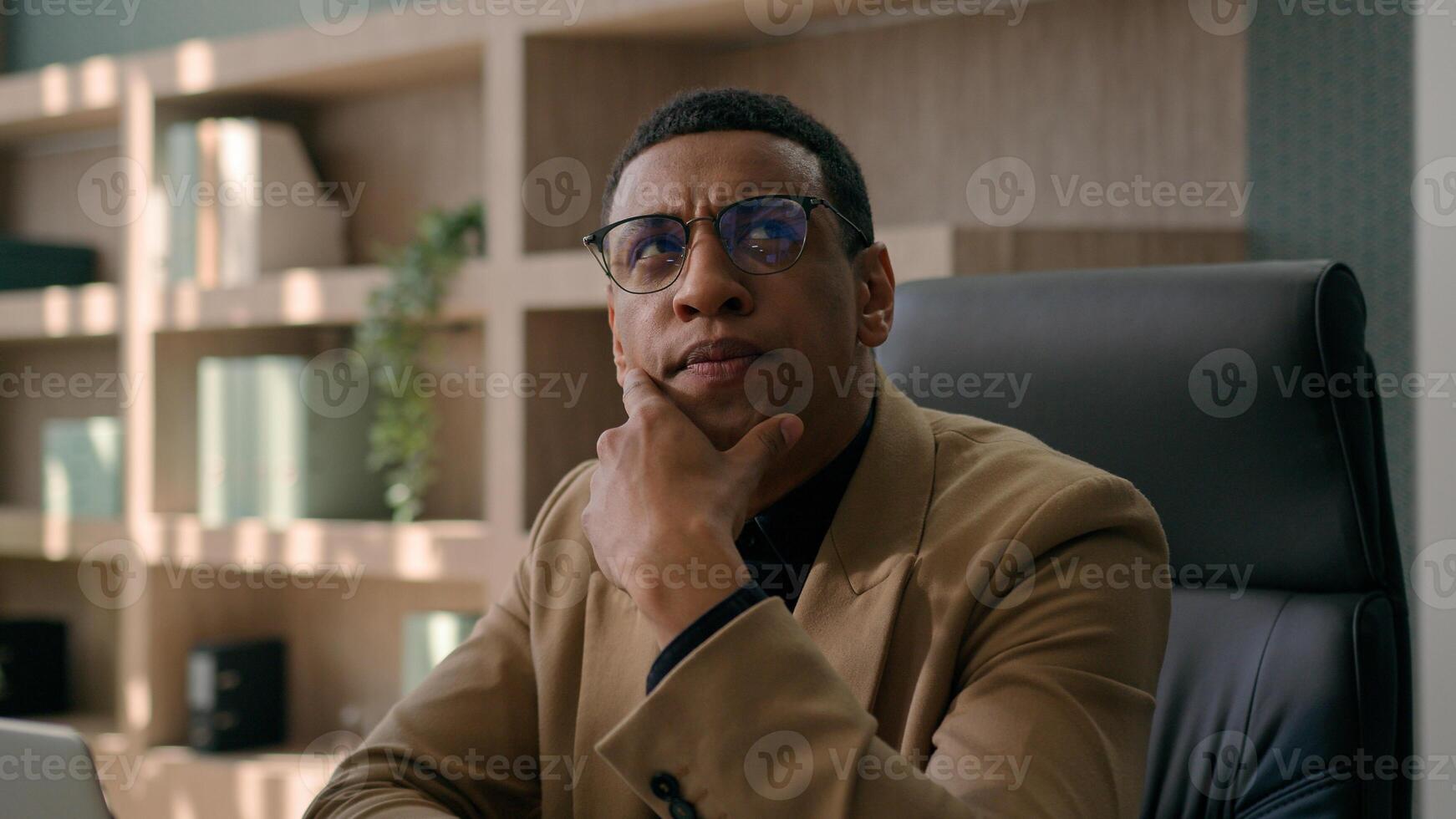 Pensive thoughtful African American man work laptop in office male writer businessman business manager think ponder consider thoughts come up with idea typing article on computer happy insight gesture photo