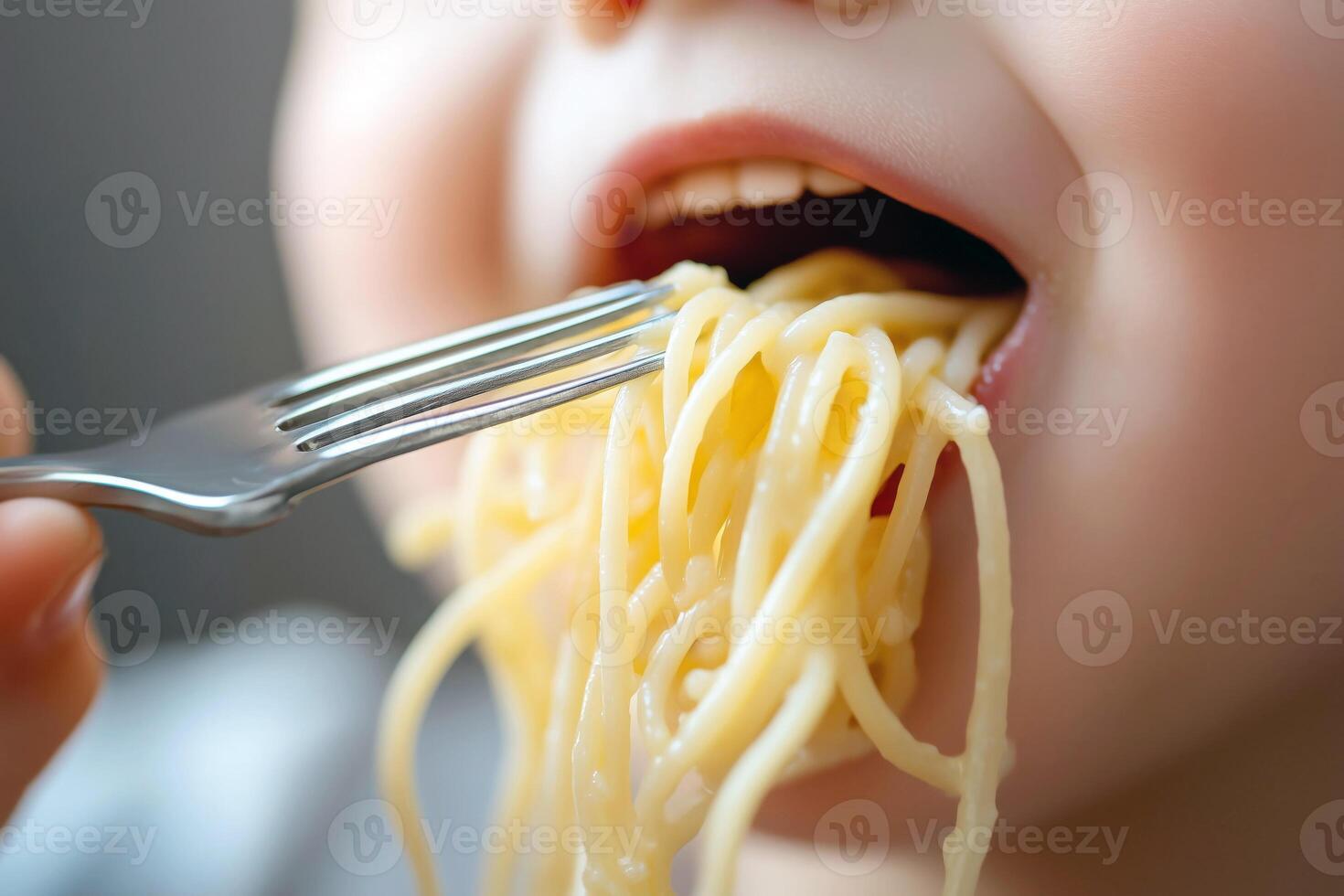 Cute toddler eating spaghetti, fork in hand, close up photo