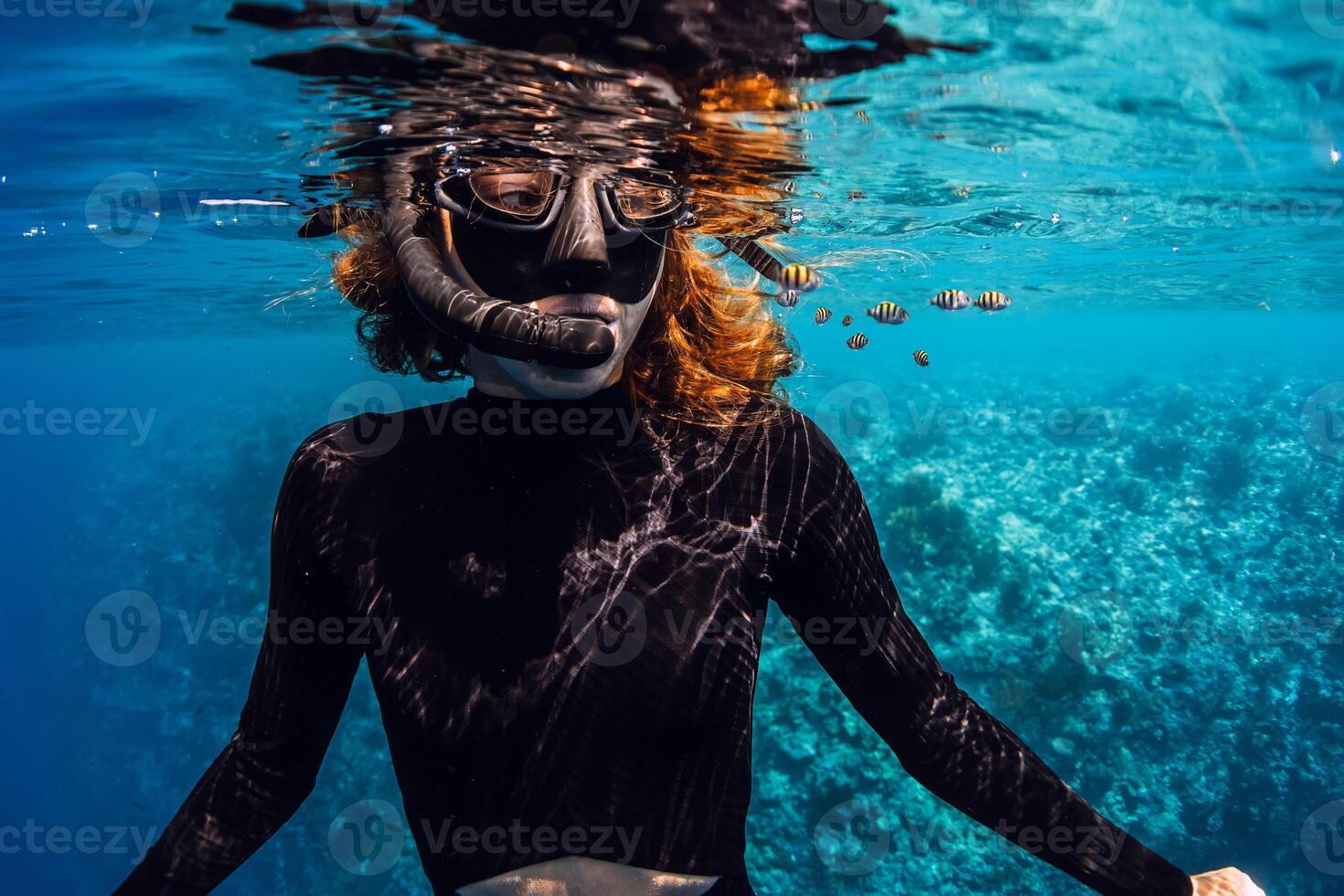 Freediver snorkeling in tropical sea with cute small fishes. photo