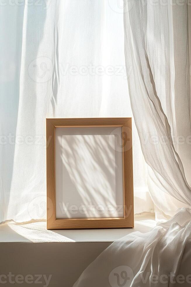 A light oak picture frame rests on a windowsill, surrounded by sheer white curtains that sway softly. Natural light pours in, creating a tranquil atmosphere perfect for adding a personal touch photo