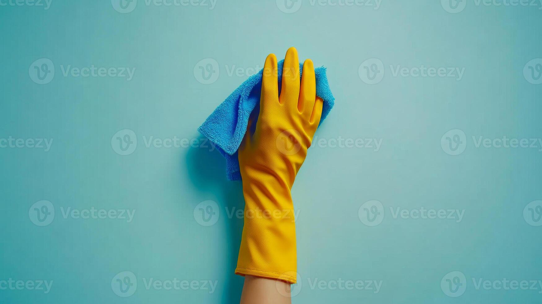 A person is holding a blue and yellow cleaning cloth. The cloth is wet and the person is wearing yellow gloves. Concept of cleanliness and tidiness photo