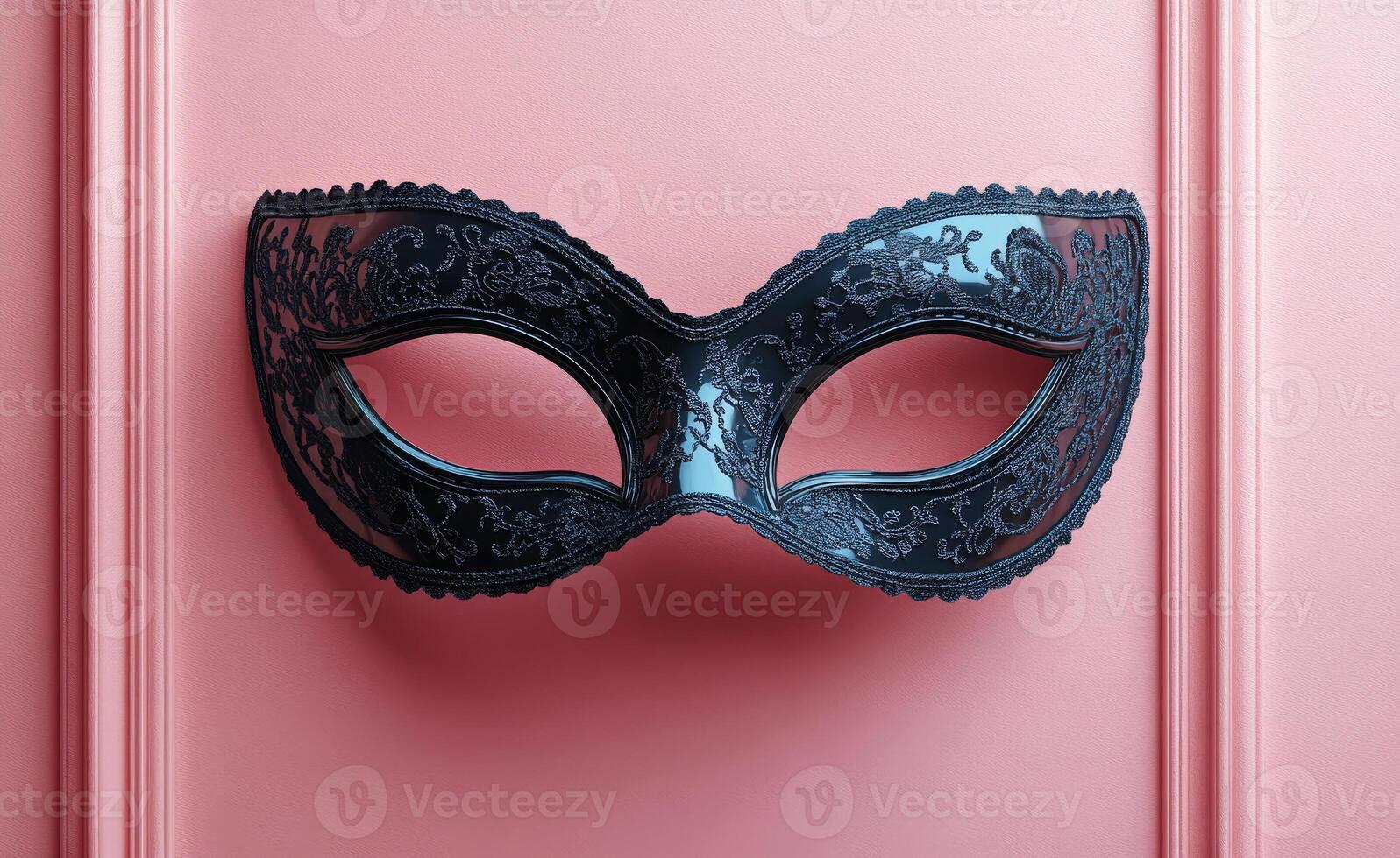 Black mask on pink wall. A detailed black mask hangs against a soft pink wall, showcasing intricate patterns and a classic design. photo