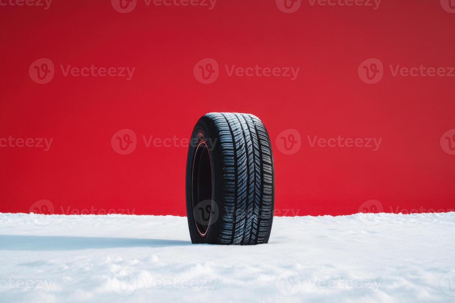 Winter tire standing on snow with vibrant red background under bright lighting photo
