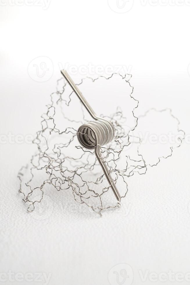 macro close up photo of vaping vaporizer single coil wire alien core coil, twisted messes coil in aluminum stainless steel concept on white background