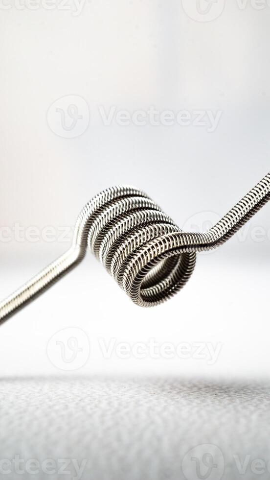macro close up photo of vaping vaporizer single coil wire alien core coil, twisted messes coil in aluminum stainless steel on white background