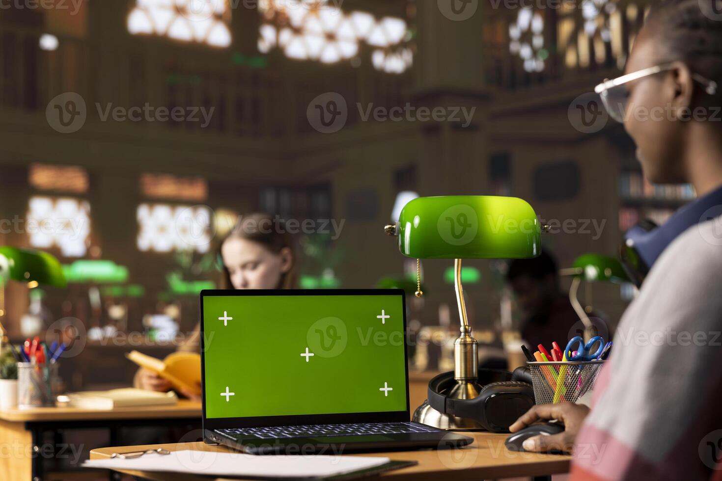 College student collecting academic data next to chroma key display, using the general database and research collection at the university library. Intellectual pupil searching for study materials. photo