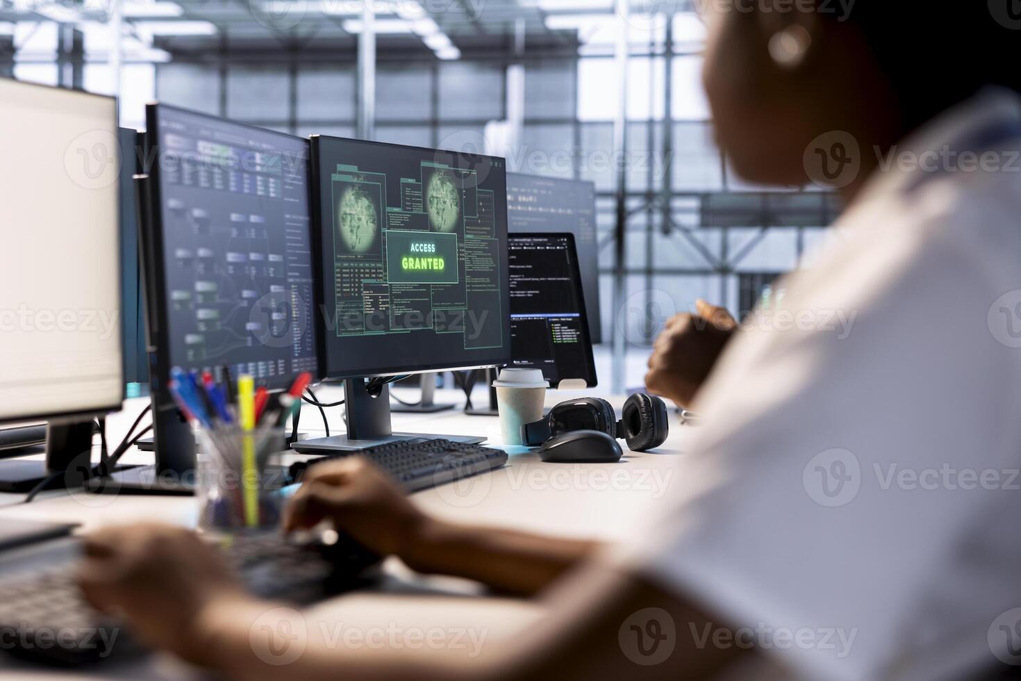 Woman in server farm getting access granted notification on PC screen, managing to access server files after they were locked by hacker using ransomware, receiving aid from IT staff members photo