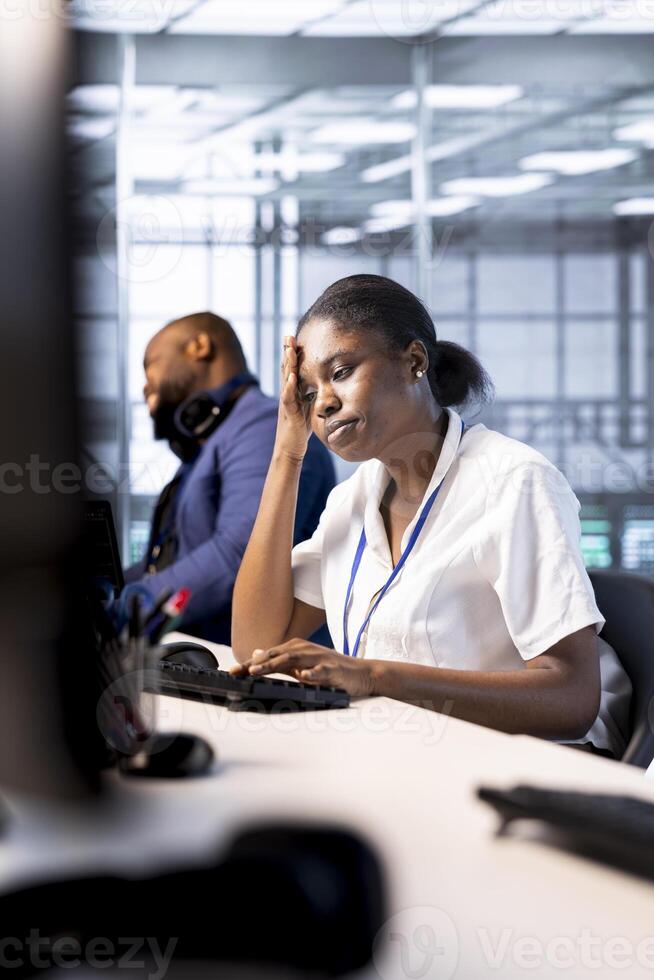 Data center technician feeling headache from stress while using programming languages on PC. Fatigued server farm worker debugging and optimizing code, feeling overworked photo