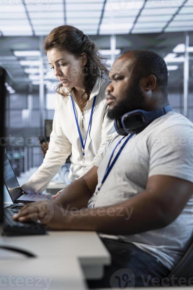 Teamworking colleagues updating AI systems, writing intricate binary code scripts on PC and laptop. Team of engineers using programming to upgrade artificial intelligence simulation model photo