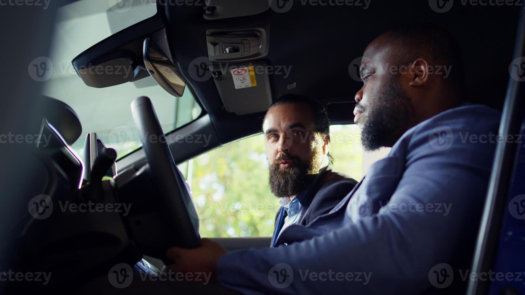 Customer discussing with sales executive concerns noticed after driving car during test drive. African american man talking with showroom salesman, telling him observed issues in vehicle, camera B photo