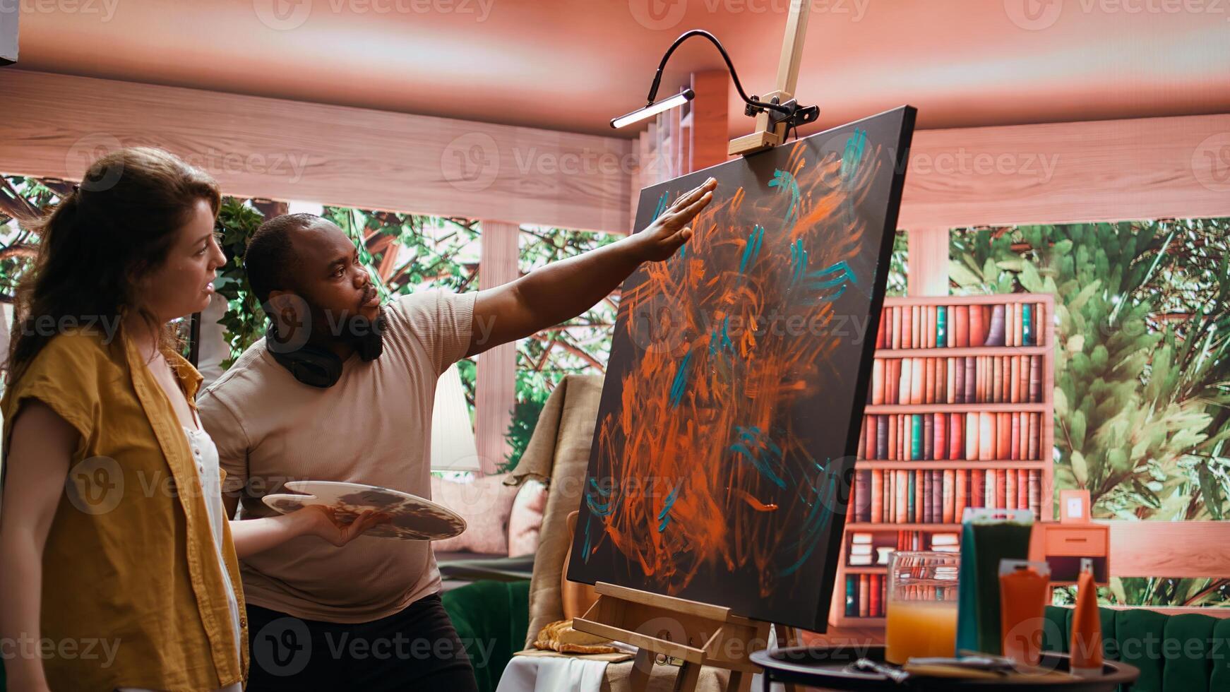 Talented artist and her apprentice engage in finger painting hobby in art and craft workshop, using modern painting technique to create abstract masterpiece. Vibrant colors on canvas. Camera B. photo