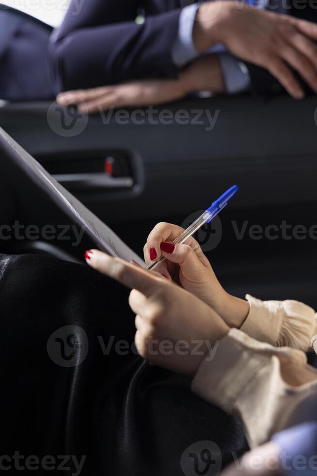 Car dealership salesperson preparing purchase paperwork and documentation after agreeing terms with customer during test drive. Close up of showroom employee giving sale contract for client to sign photo