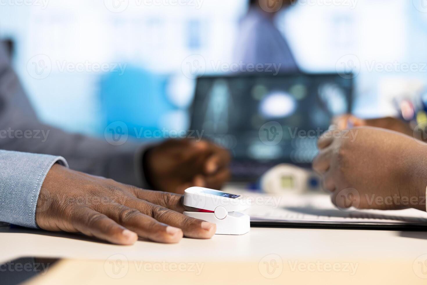 General practitioner takes the oxygen saturation measurements and pulse rate using an oximeter during checkup, consulting young man with modern medical equipment. Oxygen levels indicator. photo