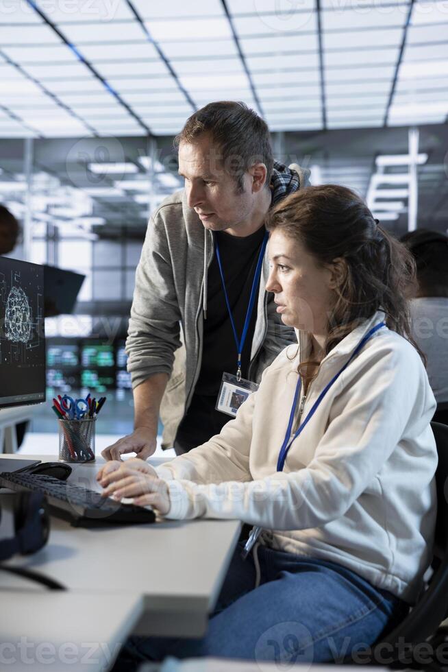 Worker requesting help from senior engineer to fix error in high tech AI data center. Employee in need of aid from IT specialist to repair artificial intelligence supercomputers photo