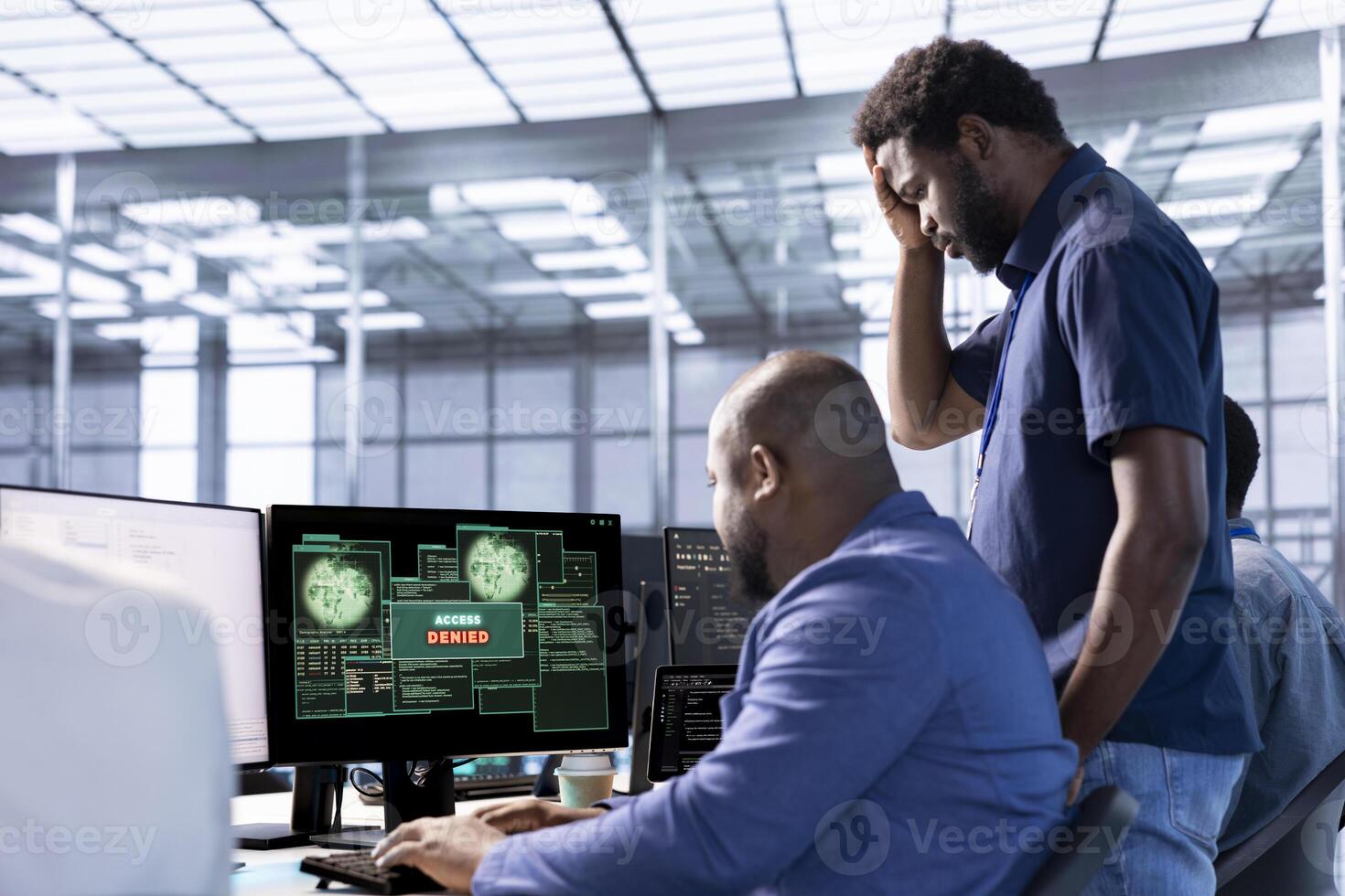 Upset coworkers in data center getting access denied notification on PC screen, trying to access server files after they were locked by hacker using ransomware, doing face palm gesture photo