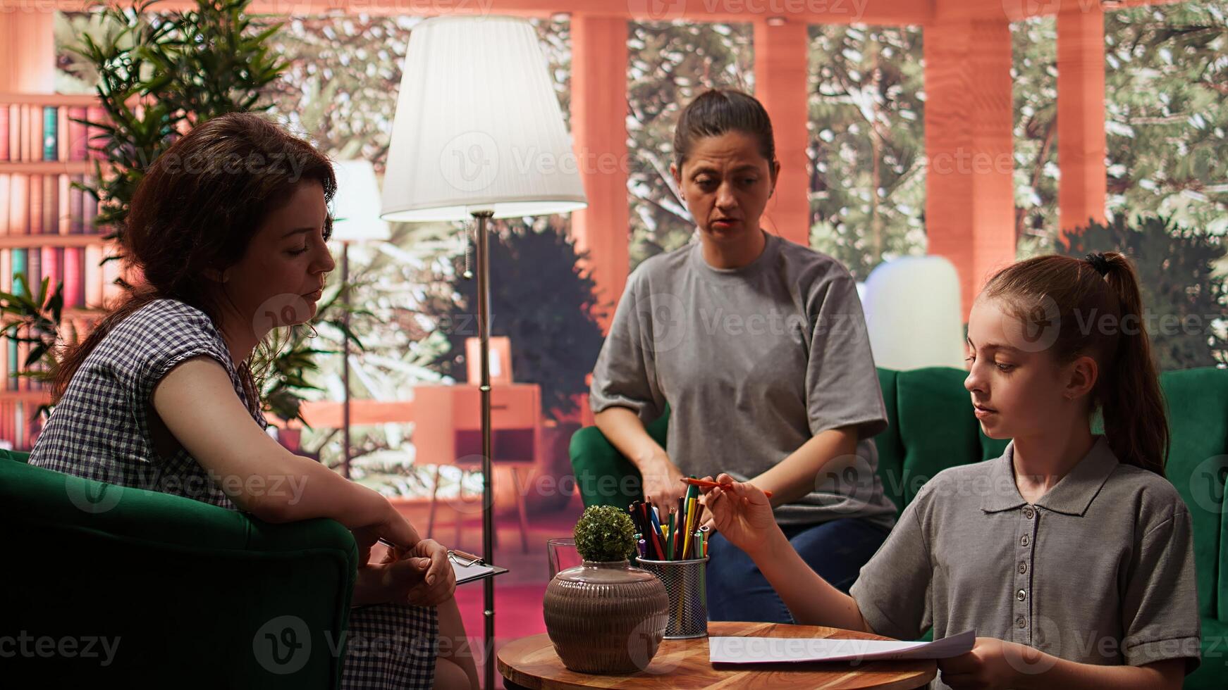 Teenage girl engages in a drawing activity as part of creative therapy session. Counseling with her mother and therapist focuses on using artwork for stress relief and emotional management. Camera B. photo