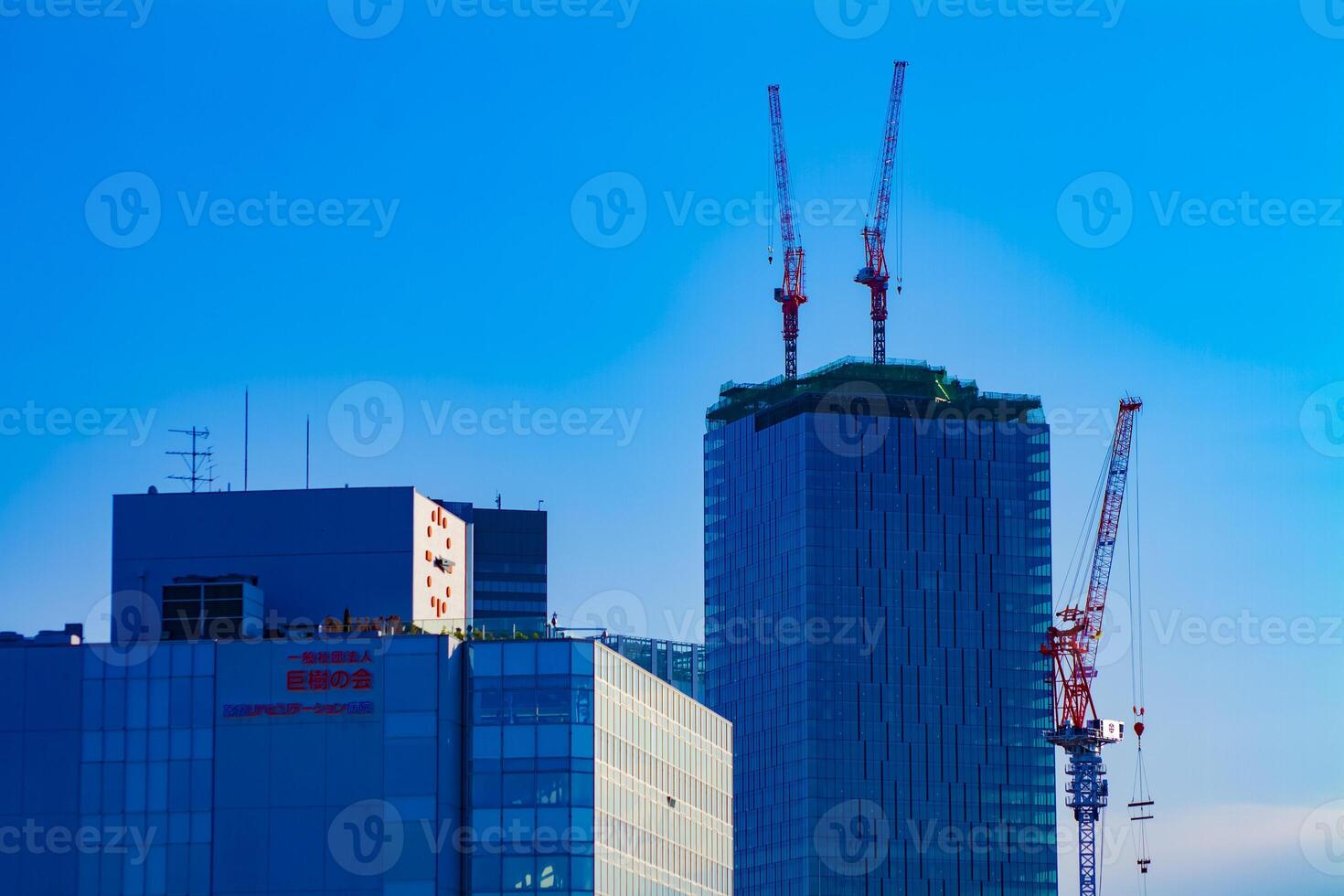 A time lapse of moving cranes on the top of building behind the blue sky in Tokyo photo