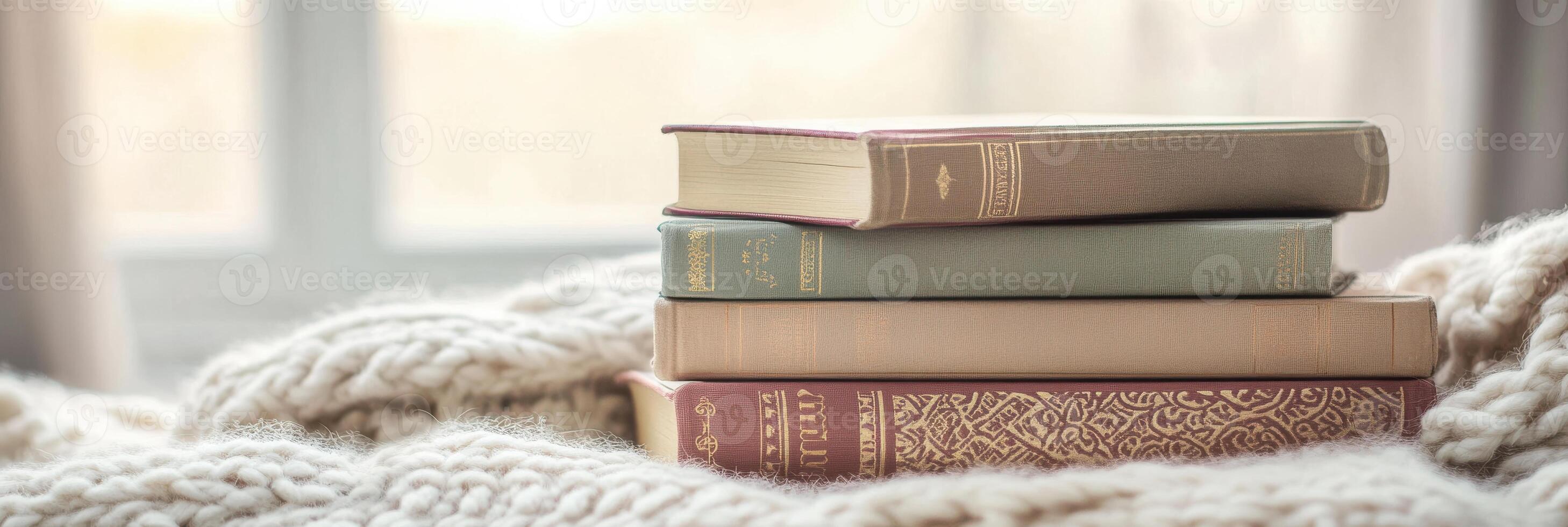 Stack of vintage books on soft blanket by window reflecting cozy reading concept photo