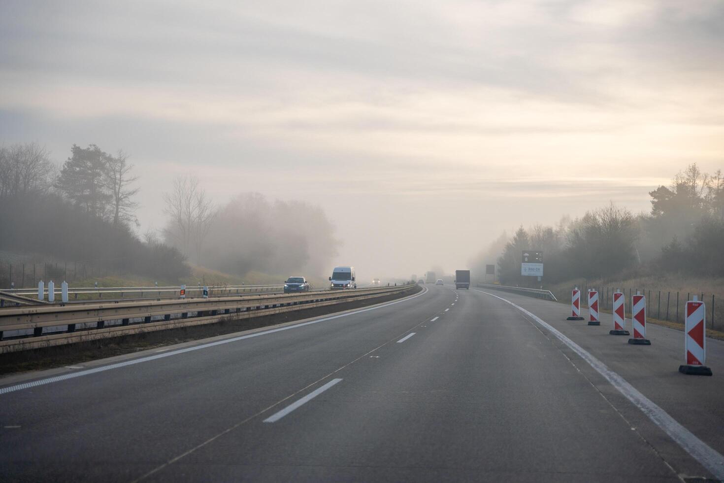 Germany, Europe - 20.12.2024. Back tail view of many cars driving fast on wet highway road in fog in Europe. High quality photo