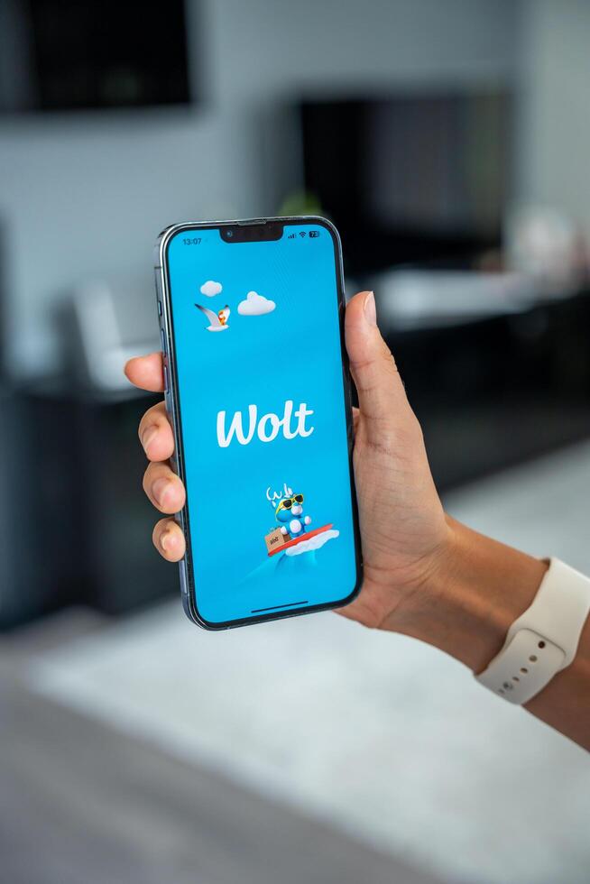 Prague, Czech republic - May 2, 2024. Woman holding iPhone with logo of application Wolt on the screen, using mobile application . High quality photo