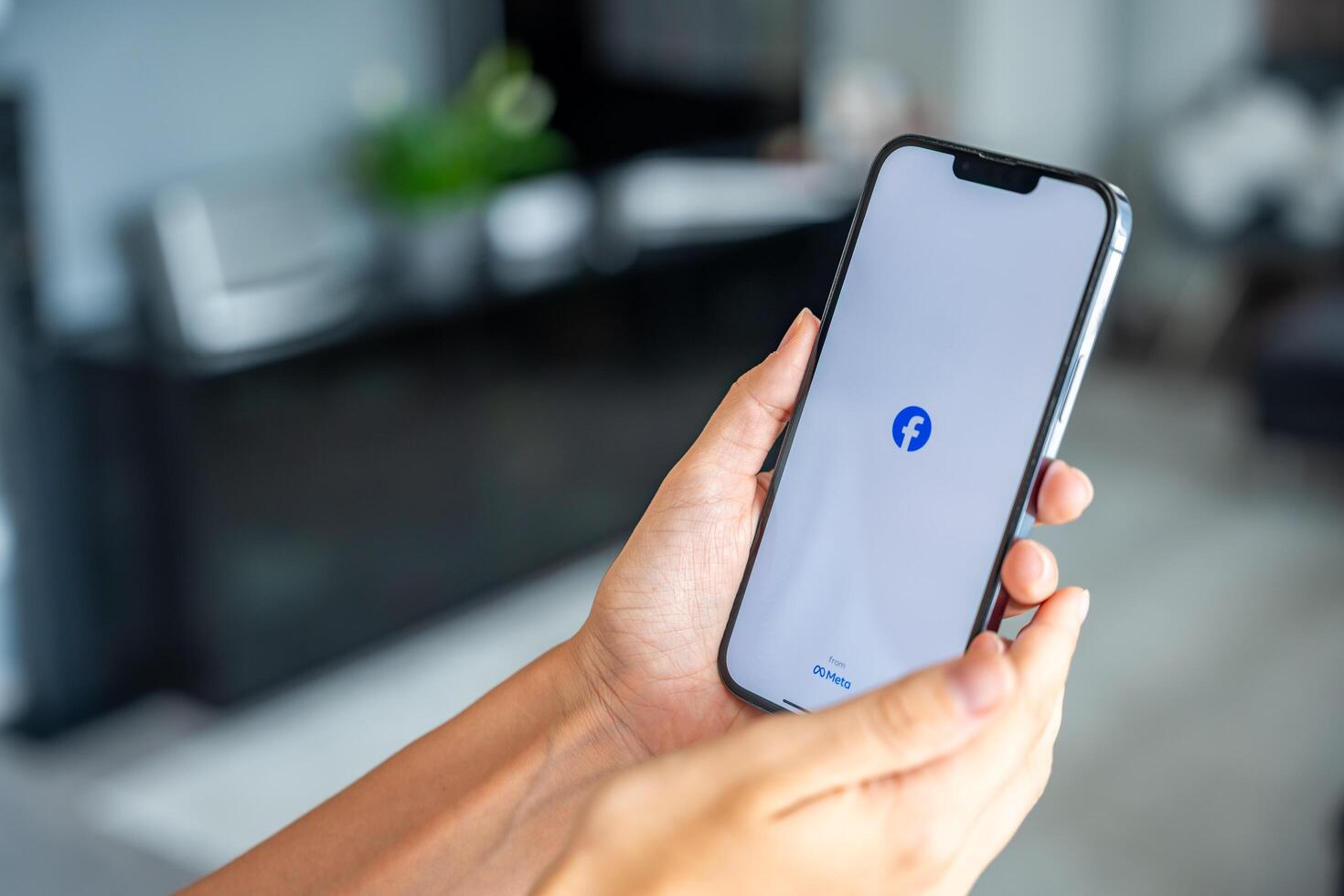 Prague, Czech republic - May 2, 2024. Woman holding iPhone with logo of application Meta Facebook on the screen, using mobile application for business home. High quality photo