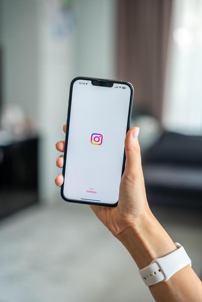 Prague, Czech republic - May 2, 2024. Woman holding iPhone with logo of application Instagram on the screen, using mobile application for business home. High quality photo