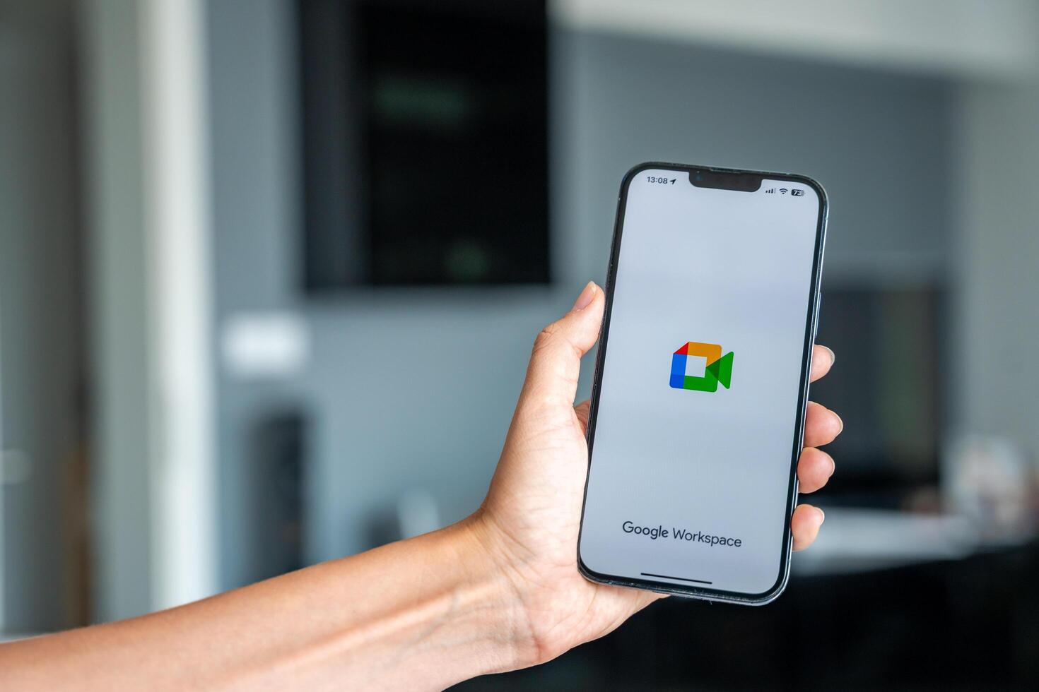 Prague, Czech republic - May 2, 2024. Woman holding iPhone with logo of application Goole Meet on the screen, using mobile application for business home. High quality photo