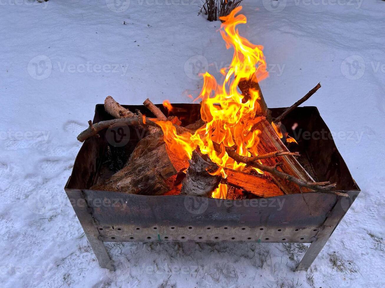Burning branches and firewood in the barbecue outside in winter photo