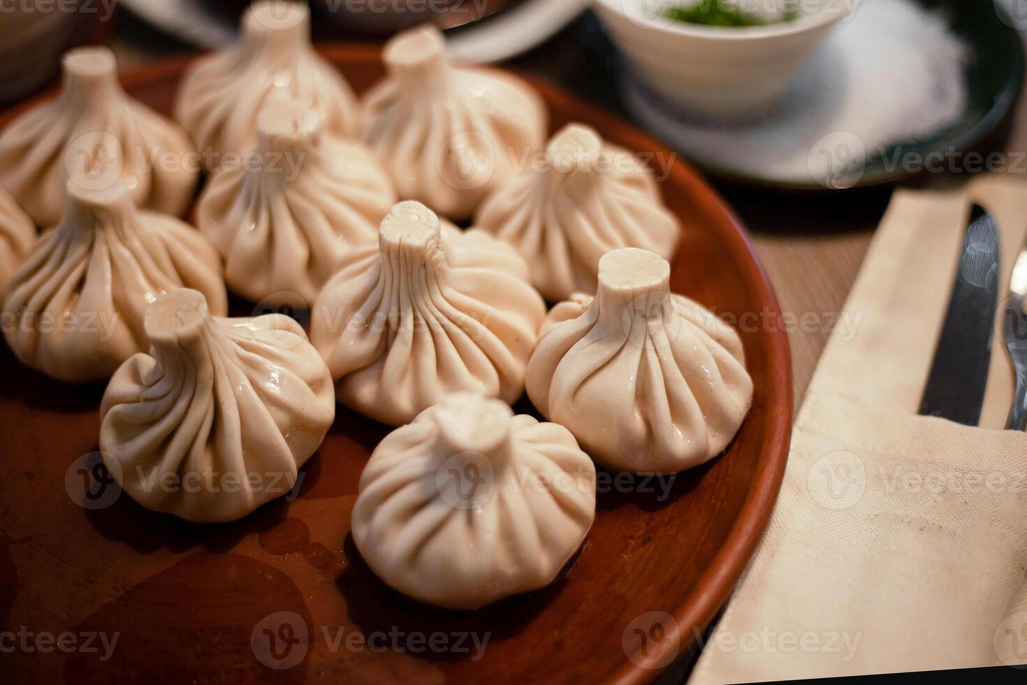 Khinkali is a dish of Georgian cuisine. Food on a plate. Boiled dough with filling. Dumplings. Lunch is on the table. A portion of khinkali in the restaurant photo