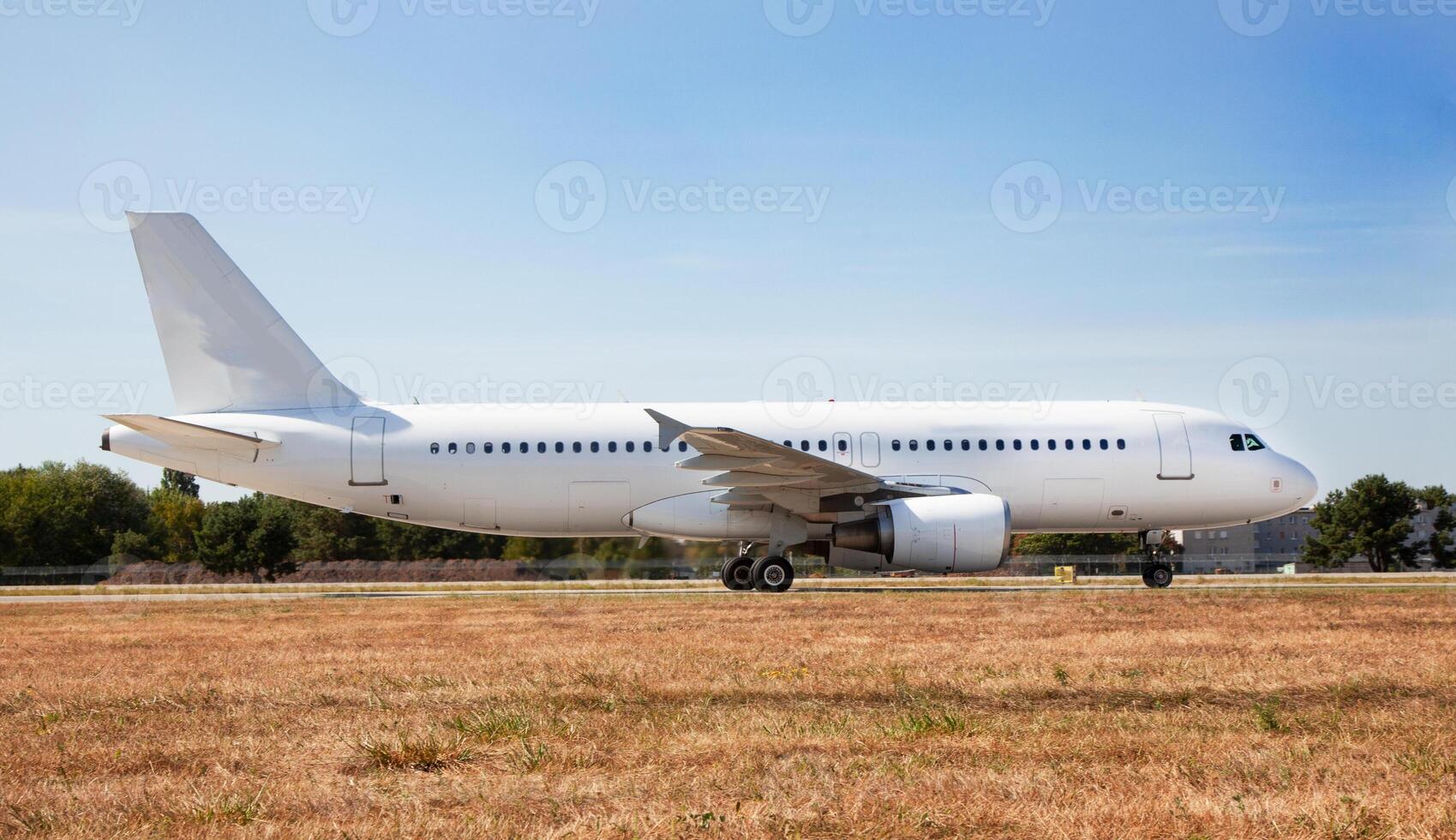 A white plane on the airport runway is taxiing. Takeoff and landing. Arrival and departure. Place for text. Passenger plane mockup. Airplane flight. Travel by air transport. Copy space photo