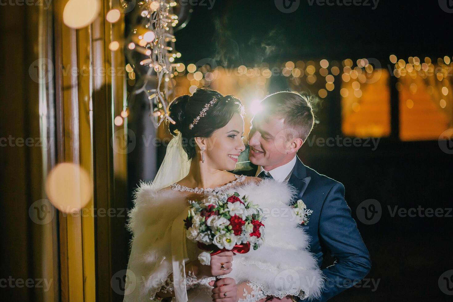 bride and groom are standing together in front of a window. photo