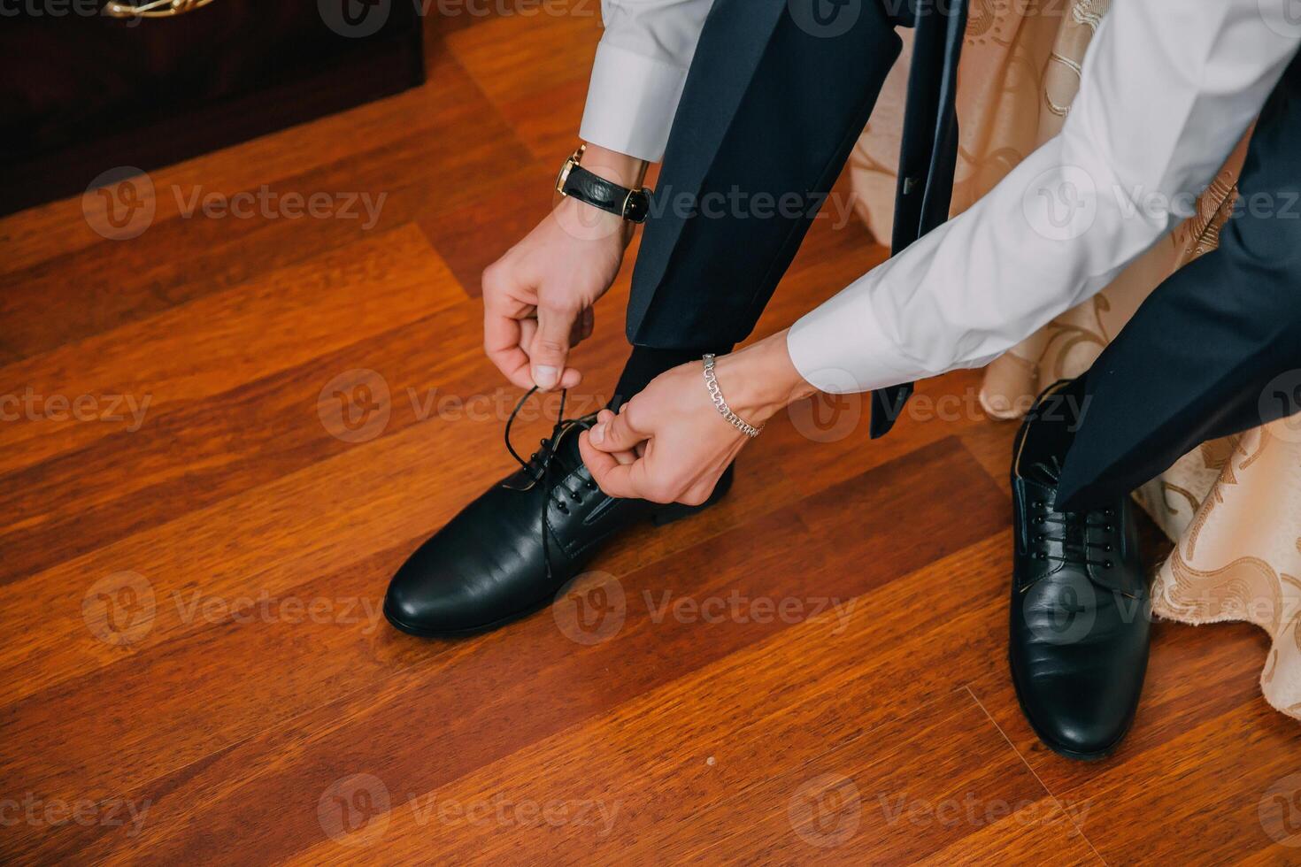A man is getting ready for a formal event, putting on his black dress shoes. photo