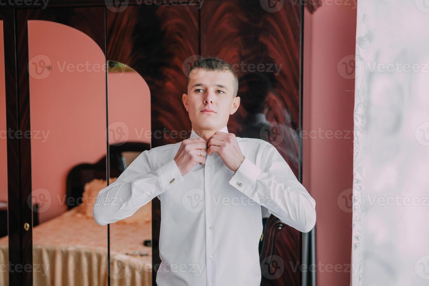 A man is getting dressed in front of a mirror. photo