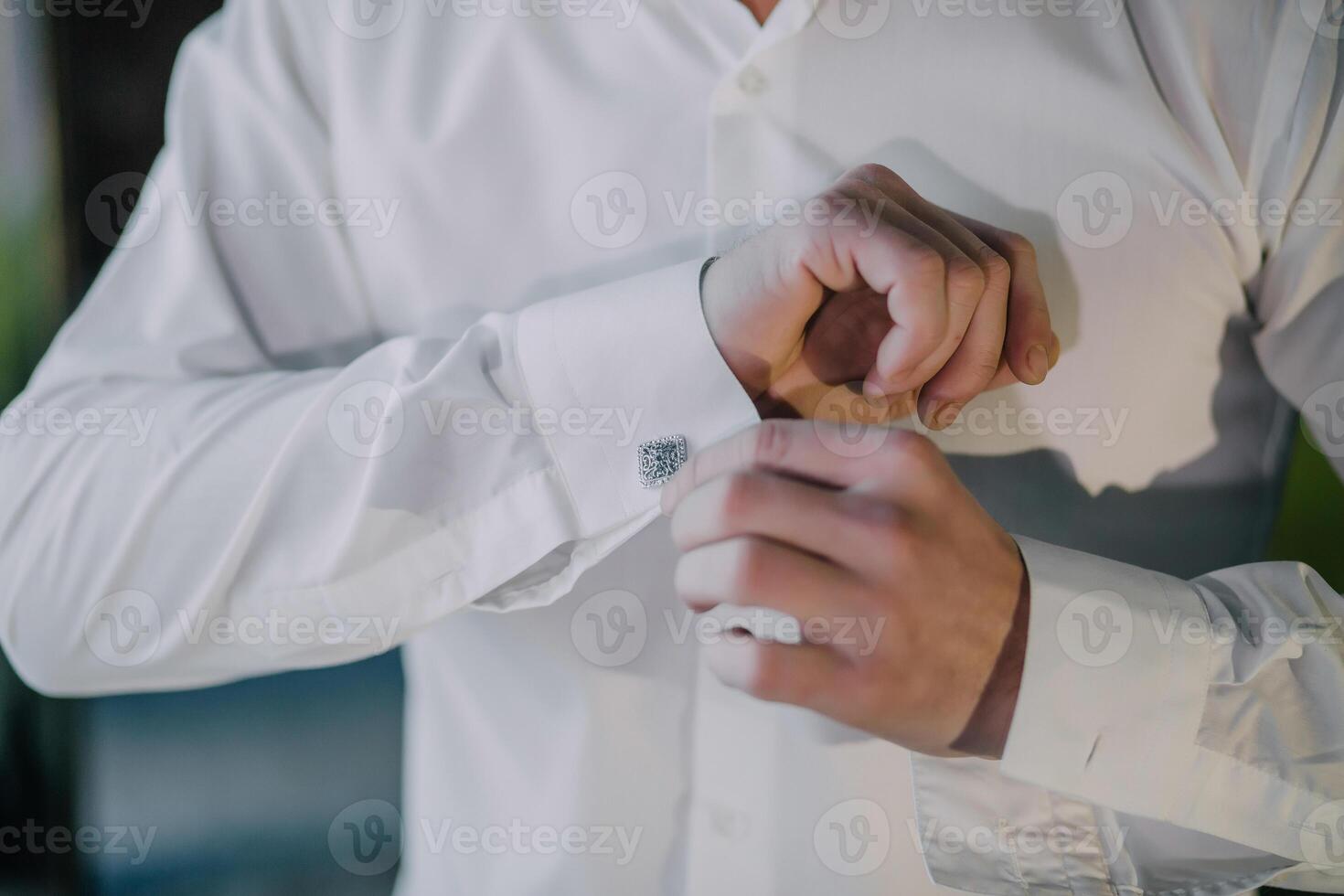 man is getting dressed in a white shirt and is putting on a cuff photo