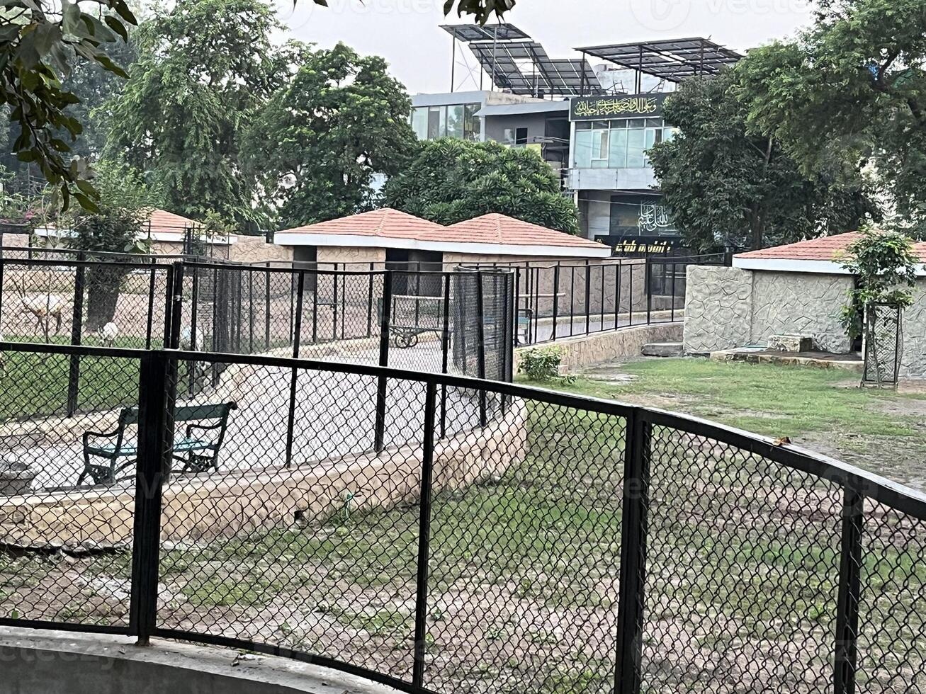 a park with a fence and benches in front of a building in Lahore on 10-10-2024 photo