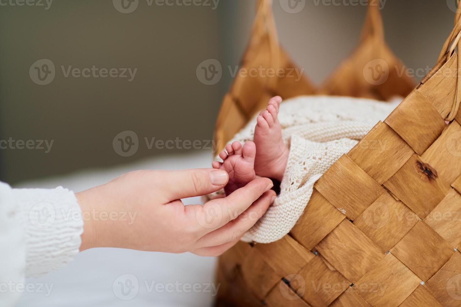 A tender close up of a babys tiny feet resting in a woven basket while an adult hand gently holds them, showcasing warmth, love, and care. photo