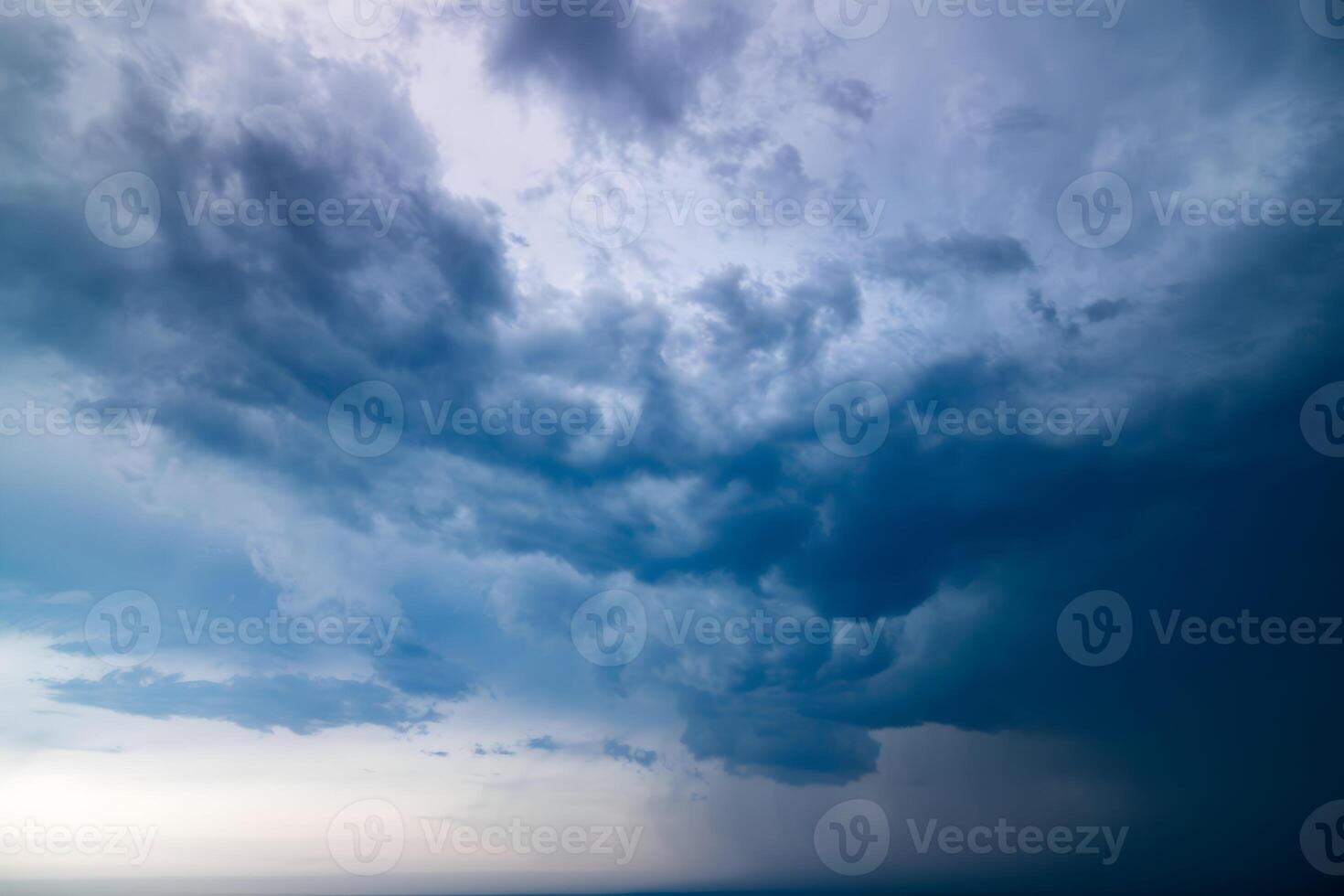 Dark stormy sky dominates, with hints of light edging through clouds photo