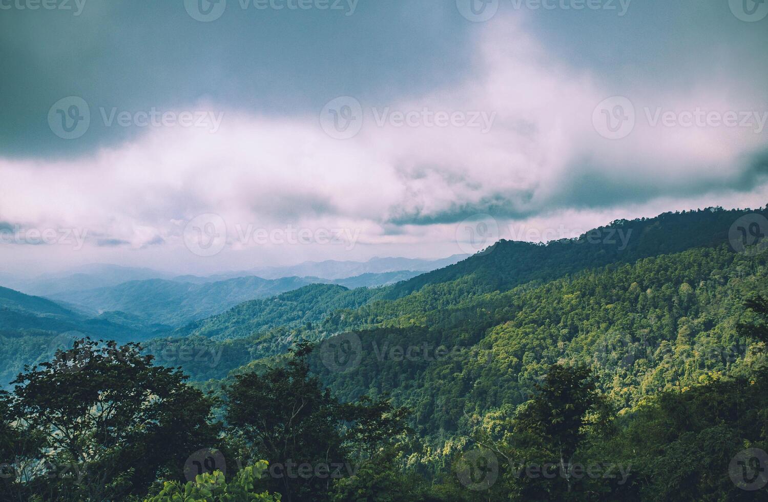 A cloudy day with tree-covered mountains. photo