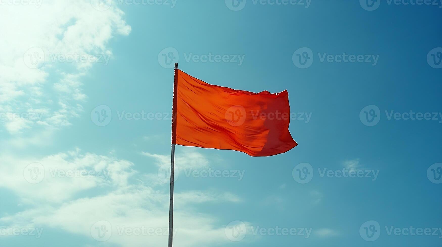 Bright Red Warning Flag Flying Against a Clear Blue Sky with Fluffy Clouds photo
