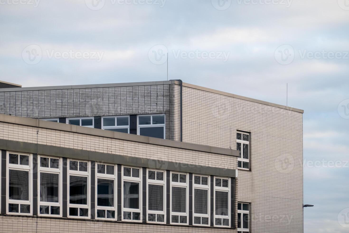 Modern building exterior with multiple windows and cloudy sky photo