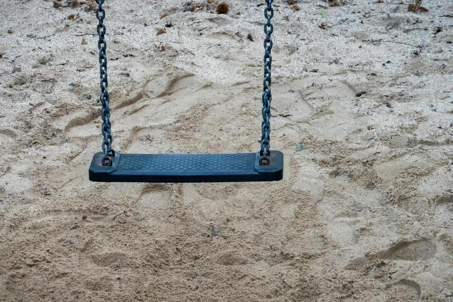 Empty swing hanging above sand in playground waiting for children photo